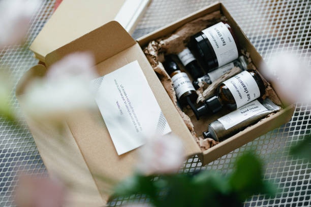 A box of essential oil bottles with labels, accompanied by an information card, placed on a table with a blurred plant in the